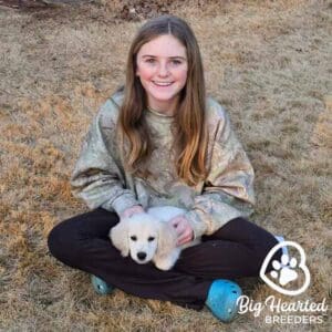 A young girl holding a mini Golden Retriever puppy on her lap