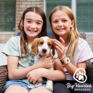 Two young girls holding a mini Golden puppy on their laps