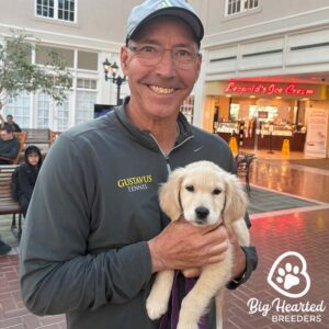 Man holding a small Golden Retriever in his arms